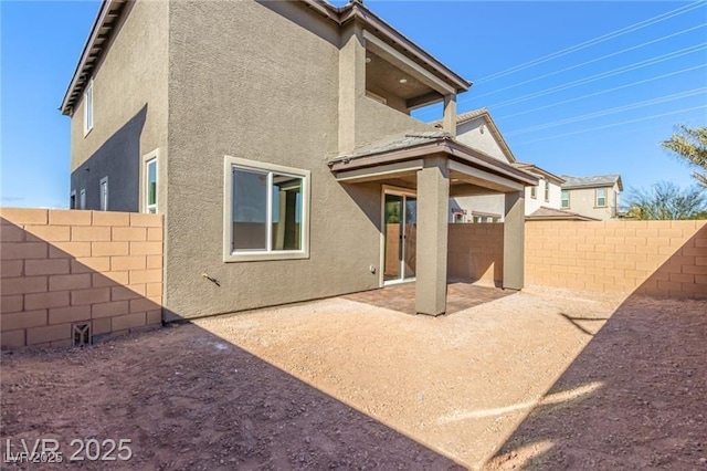 rear view of property featuring a patio, a fenced backyard, and stucco siding