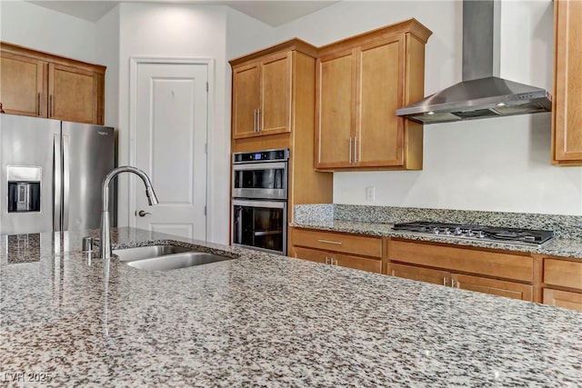 44 Strada Caruso, Henderson, NV 89011 - kitchen with light stone countertops, wall chimney range hood, a sink, stainless steel appliances, and brown cabinets