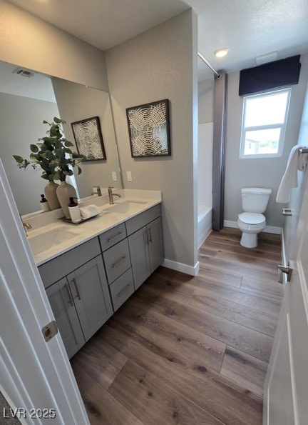 full bathroom with a sink, toilet, and wood finished floors