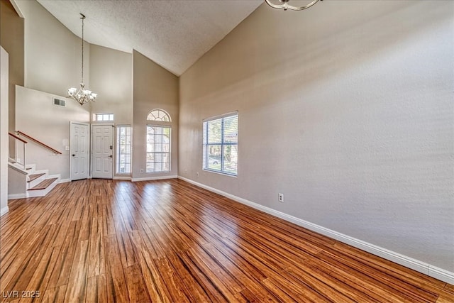 foyer entrance with an inviting chandelier, visible vents, wood finished floors, stairs, and baseboards