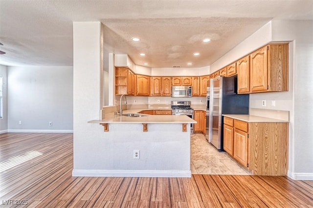 kitchen with a sink, baseboards, light wood-type flooring, and stainless steel appliances