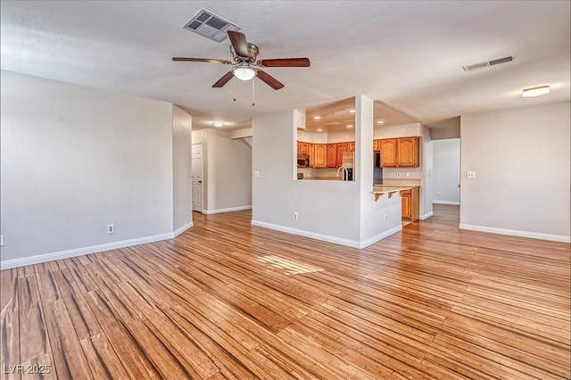 unfurnished living room featuring light wood-style flooring, visible vents, and ceiling fan