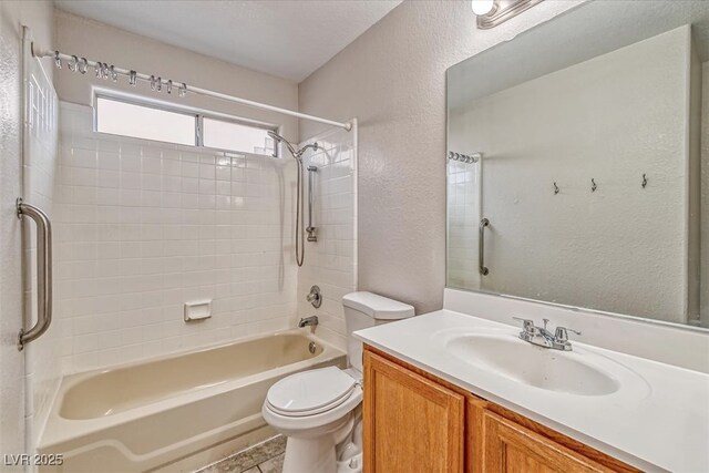 bathroom featuring a textured wall, shower / bathtub combination, vanity, and toilet