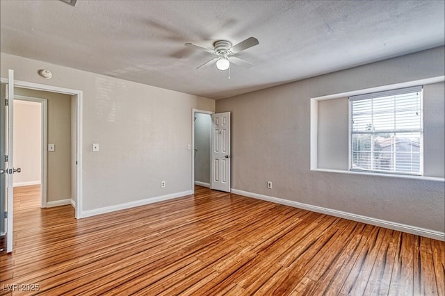 spare room featuring light wood-style floors, baseboards, a textured ceiling, and ceiling fan