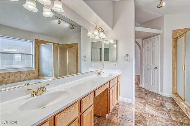 bathroom with a sink, baseboards, a shower stall, and double vanity