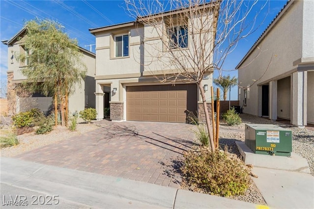 traditional home featuring stucco siding, an attached garage, decorative driveway, and stone siding