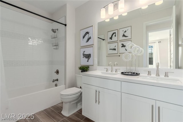 full bathroom featuring wood finished floors, toilet, bathtub / shower combination, and a sink