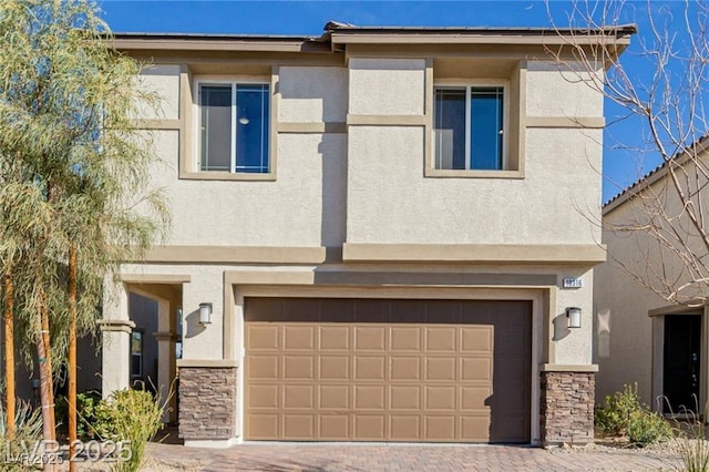 view of front of home featuring a garage, stone siding, stucco siding, and decorative driveway