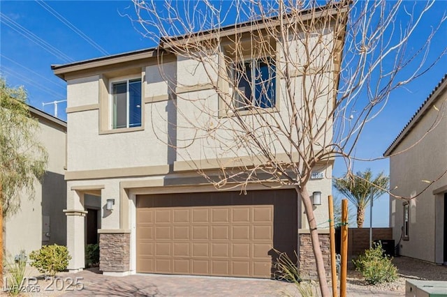 view of front of property featuring decorative driveway, stone siding, an attached garage, fence, and stucco siding