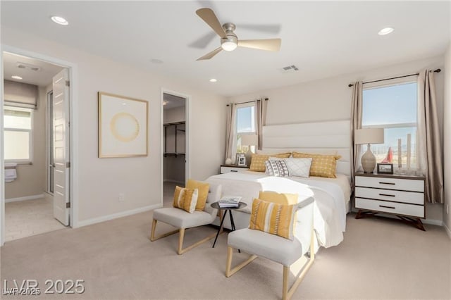 bedroom featuring a walk in closet, visible vents, baseboards, and light carpet