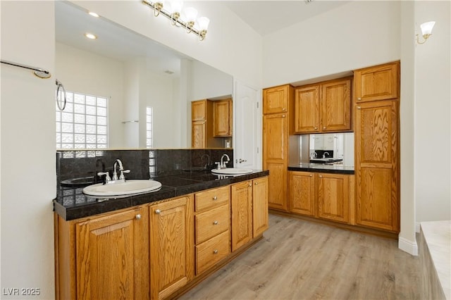 full bathroom with tasteful backsplash, wood finished floors, double vanity, and a sink