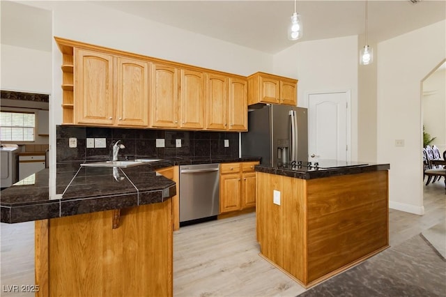 kitchen featuring tasteful backsplash, a peninsula, a center island, a sink, and stainless steel appliances