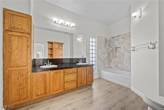 bathroom with a sink, toilet, double vanity, and wood finished floors