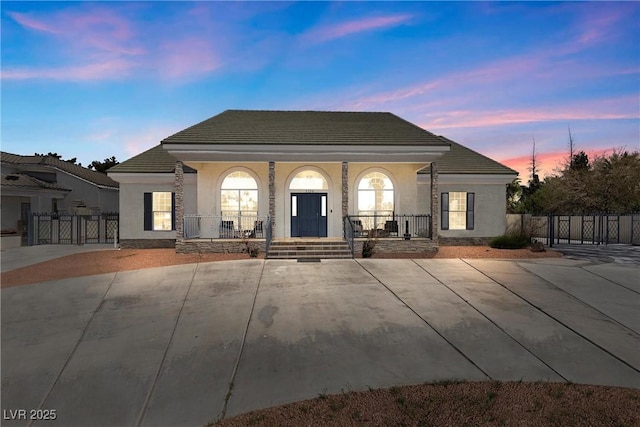 rear view of property with fence, covered porch, a gate, and stucco siding