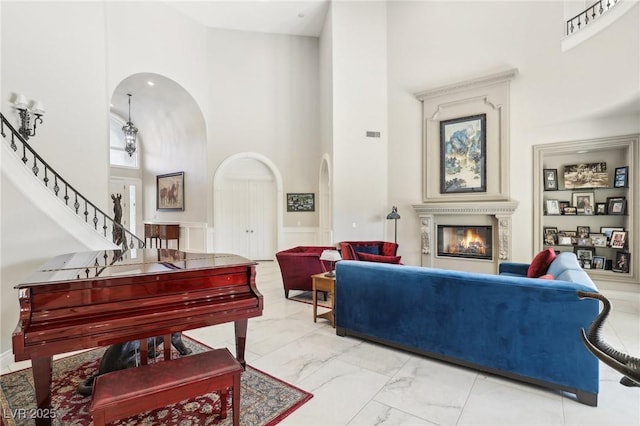 2338 Dolphin Ct, Henderson, NV 89074 - living area featuring a towering ceiling, marble look tile flooring, arched walkways, a glass covered fireplace, and stairs