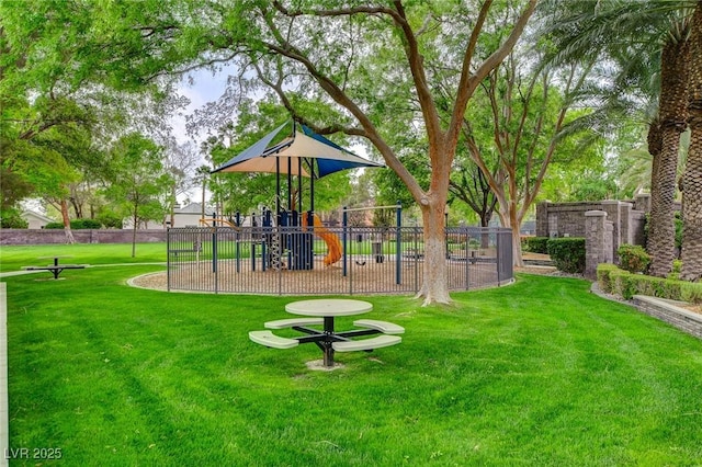 view of property's community with fence, playground community, and a yard
