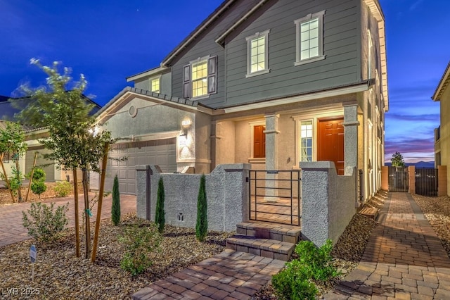 traditional-style home with a gate, a fenced front yard, stucco siding, an attached garage, and driveway