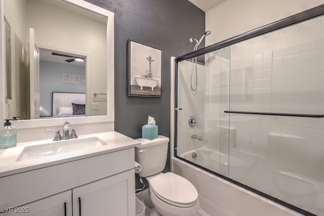 bathroom featuring a textured wall, toilet, vanity, and enclosed tub / shower combo
