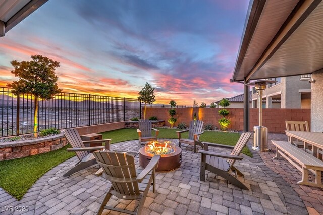 patio terrace at dusk featuring a fenced backyard and a fire pit