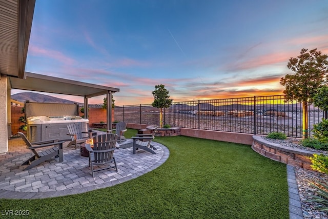 yard at dusk with a patio area, a fenced backyard, and a hot tub