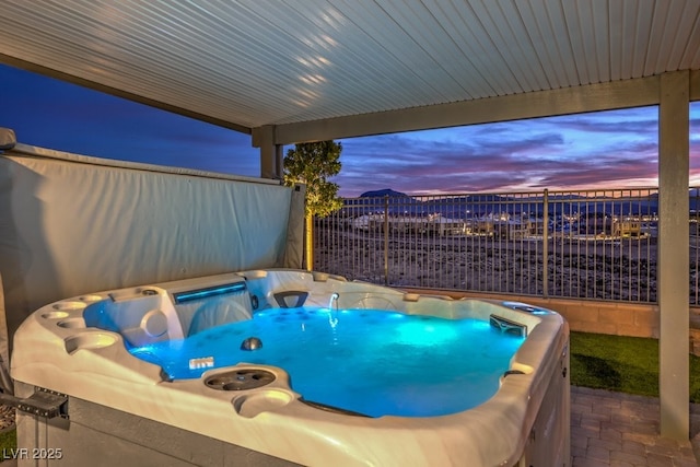 patio terrace at dusk featuring a hot tub