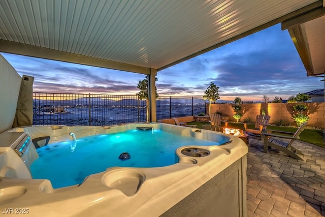 pool at dusk with a fenced backyard, a patio area, and a hot tub