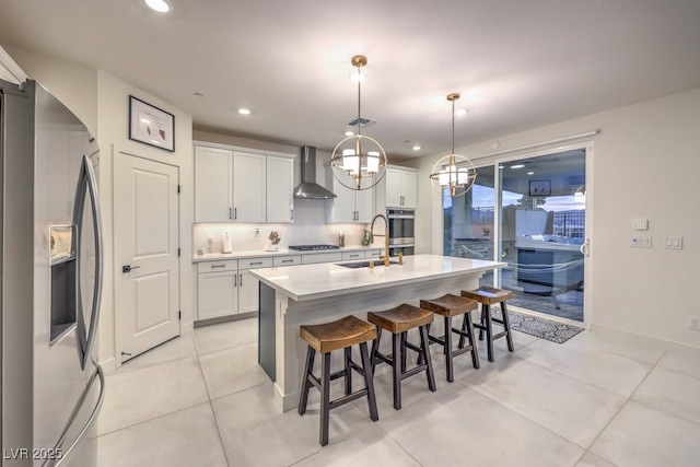 kitchen with a kitchen breakfast bar, wall chimney range hood, white cabinets, appliances with stainless steel finishes, and light countertops