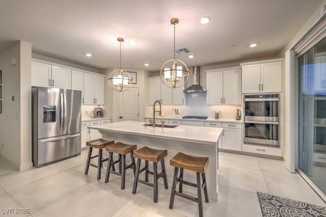 kitchen with stainless steel appliances, visible vents, a sink, wall chimney exhaust hood, and decorative backsplash