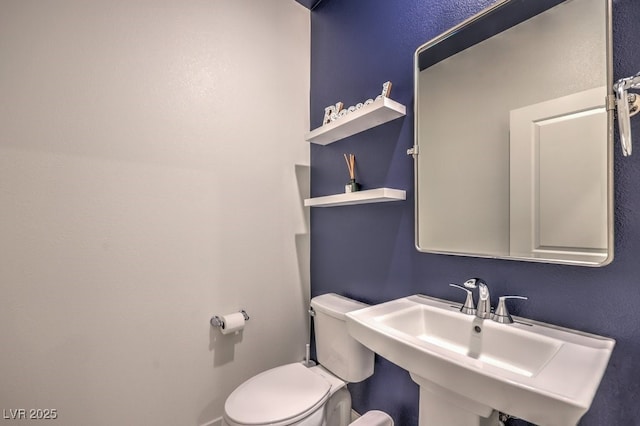 bathroom with a sink, toilet, and baseboards