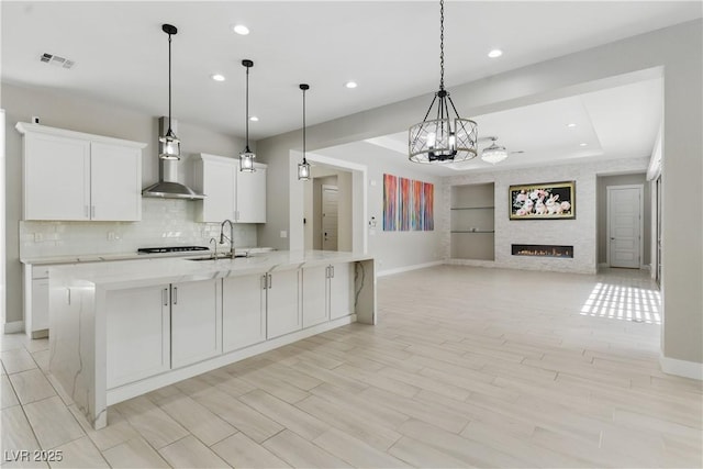 kitchen with white cabinets, built in shelves, wall chimney exhaust hood, recessed lighting, and baseboards