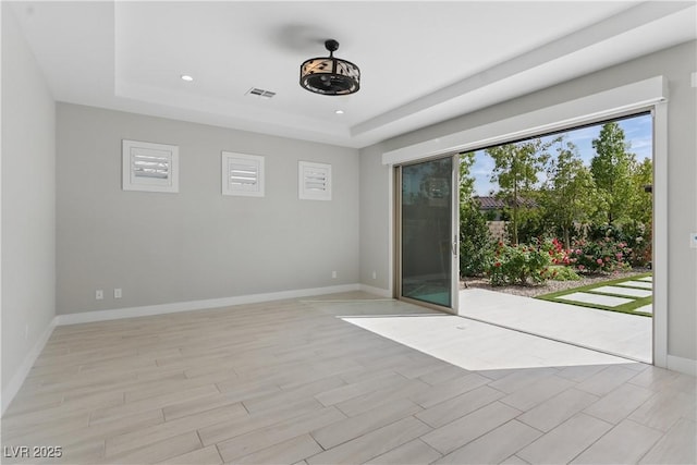 unfurnished room with visible vents, recessed lighting, baseboards, and a tray ceiling