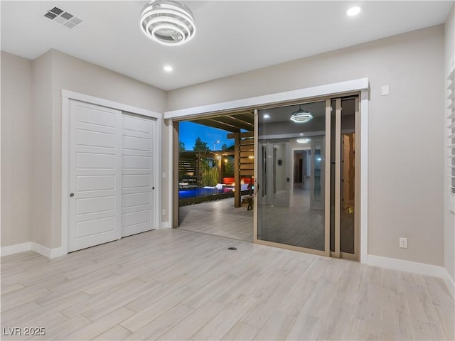 unfurnished bedroom with baseboards, a closet, wood finished floors, and visible vents