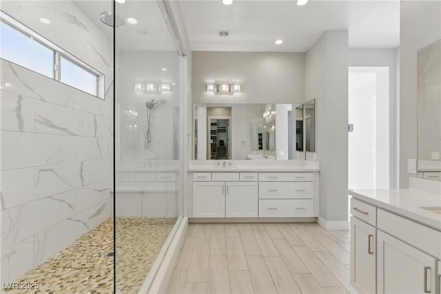 full bath with walk in shower, two vanities, a sink, and visible vents