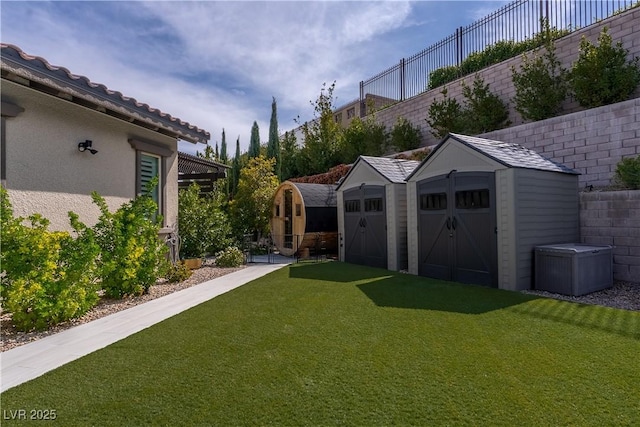 view of yard with a detached garage, fence, an outbuilding, and a shed