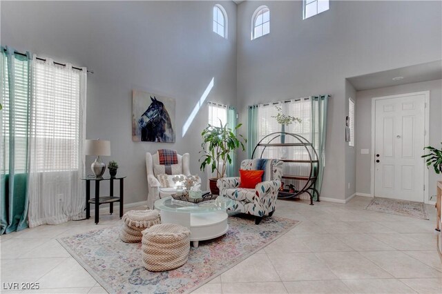 sitting room with baseboards, tile patterned flooring, and a high ceiling