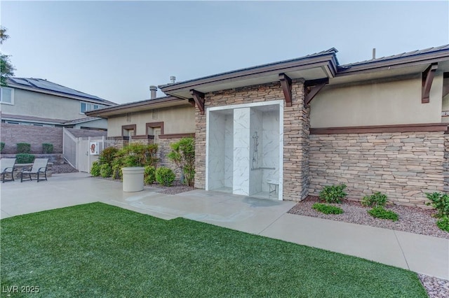 exterior space featuring a patio, fence, stucco siding, and stone siding