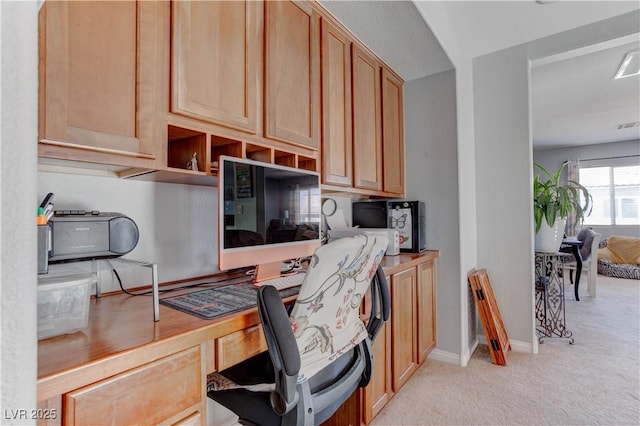 office area with baseboards, built in study area, and light colored carpet