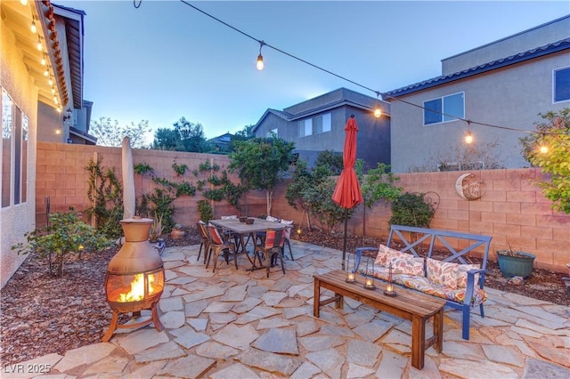 view of patio with a fire pit, a fenced backyard, and outdoor dining area