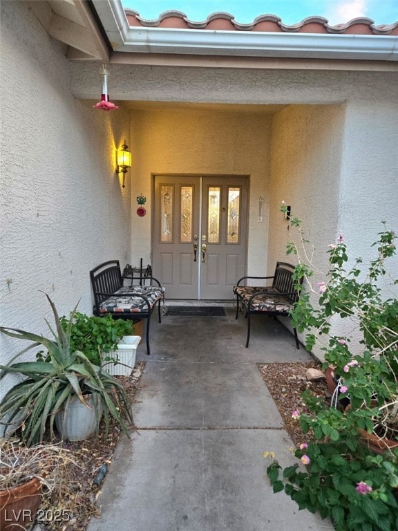 doorway to property featuring stucco siding and a porch