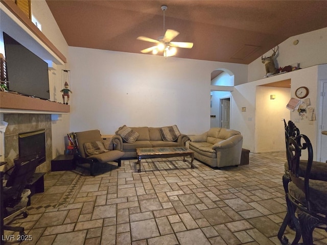 living room featuring arched walkways, ceiling fan, lofted ceiling, and a fireplace