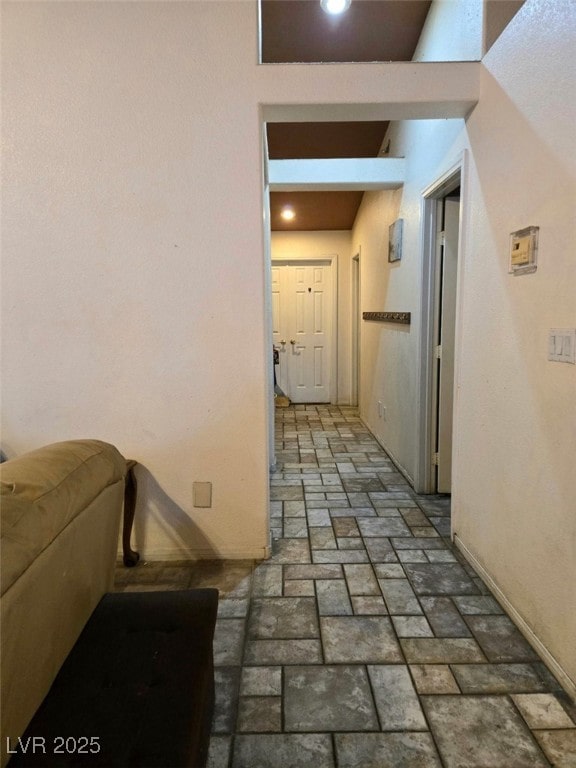 corridor featuring baseboards and brick floor