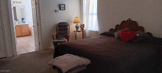 bedroom featuring light colored carpet, ensuite bathroom, and light tile patterned flooring