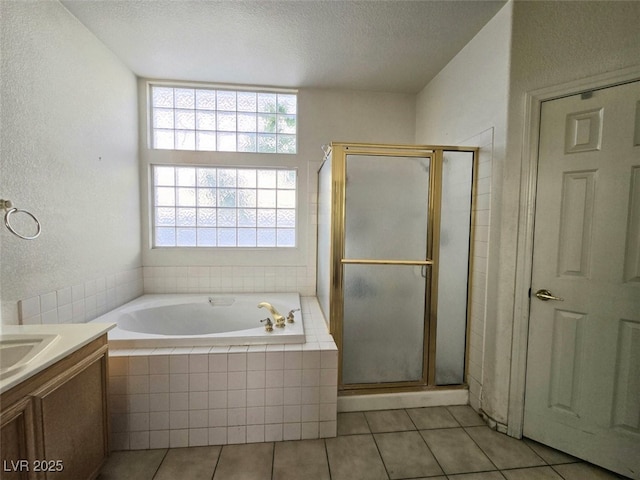 bathroom featuring tile patterned flooring, vanity, a textured ceiling, a garden tub, and a stall shower