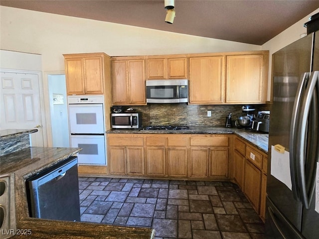 kitchen with decorative backsplash, dark stone counters, lofted ceiling, and stainless steel appliances