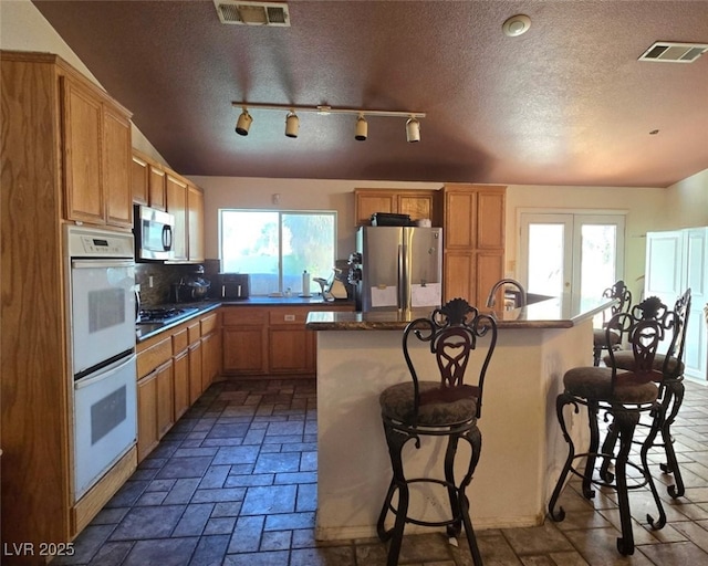 kitchen with appliances with stainless steel finishes, a breakfast bar area, and visible vents