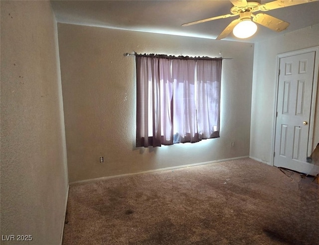 carpeted empty room with a ceiling fan and baseboards
