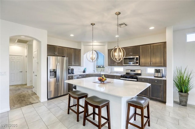 kitchen featuring a kitchen breakfast bar, dark brown cabinets, appliances with stainless steel finishes, and light countertops