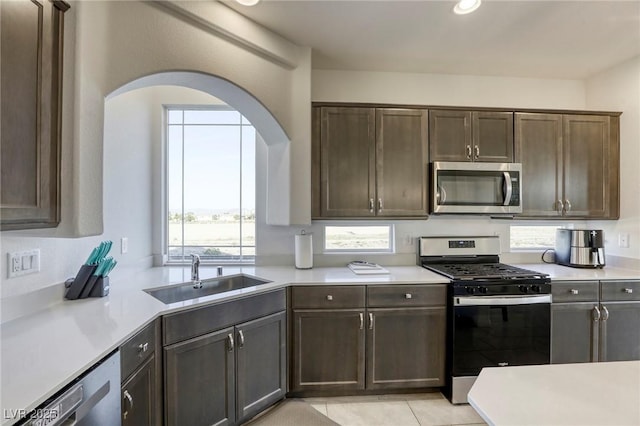 kitchen with light countertops, a sink, appliances with stainless steel finishes, and a healthy amount of sunlight