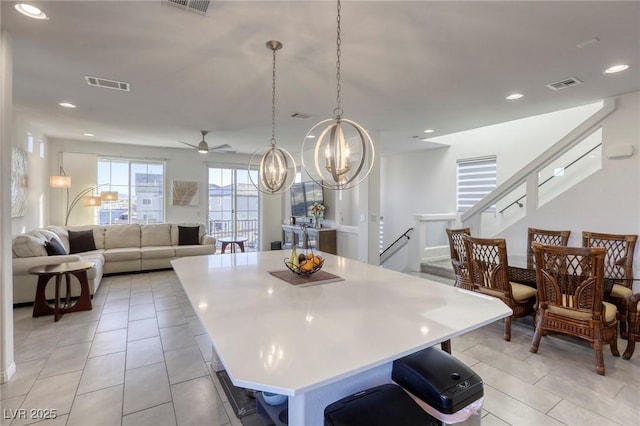 kitchen featuring visible vents, ceiling fan with notable chandelier, light tile patterned flooring, and a kitchen island