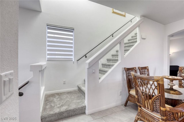 stairs with arched walkways, tile patterned floors, and baseboards